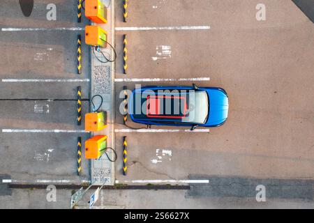 Elektroauto mit entladener Batterie wird an einer öffentlichen Ladestation mit Strom versorgt. Blinkende rote Anzeige auf dem Dach zeigt an, dass Strom benötigt wird Stockfoto