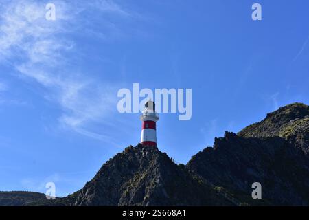 Ein majestätischer Leuchtturm, der hoch steht und Schiffe durch die turbulente See führt. Das Hotel liegt am Cape Palliser, Wairarapa, Neuseeland Stockfoto