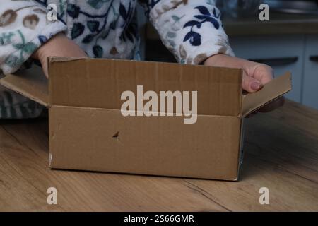 Eine Frau öffnet einen Karton. Paketzustellung. Nahaufnahme. Stockfoto