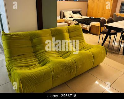 Helle und moderne Einrichtung mit einem einzigartigen grünen Sofa, einem gut angeordneten Schlafzimmer und stilvollen Möbeln, die ein lebendiges und funktionelles Leben schaffen Stockfoto