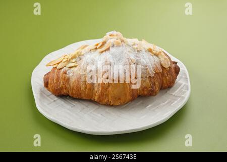 Mandelcroissant mit Puderzucker auf weißem Teller Stockfoto
