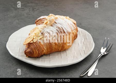 Mandelcroissant mit Puderzucker auf weißem Teller Stockfoto