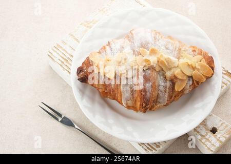 Mandelcroissant mit Puderzucker auf weißem Teller Stockfoto
