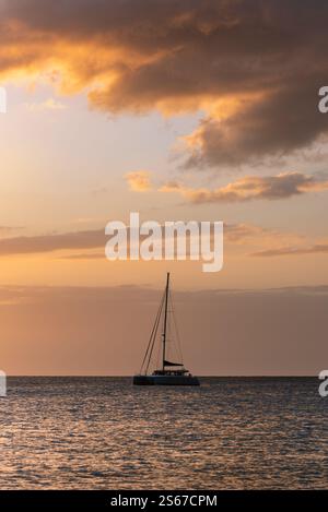 Silhouette eines Segelbootes auf einem ruhigen Ozean bei einem goldenen Sonnenuntergang. Ideal für Reisen, Entspannung und malerische maritime Themen. Stockfoto