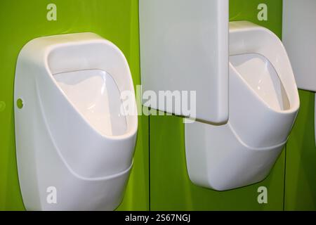 Zwei weiße Urinale an einer hellgrünen Wand. Stockfoto