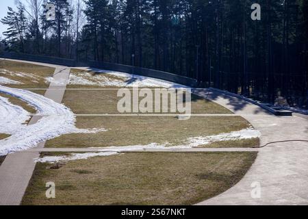 Eine teilweise schneebedeckte Bobbahn, die durch ein bewaldetes Gebiet führt. Stockfoto