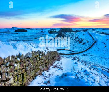Blick auf die Hadrian's Wall im Winter bei Sonnenaufgang von Cuddy's Crags nach Osten in Richtung Housesteads Fort mit Schnee, Eis und Sonnenaufgang in Northumberland Stockfoto