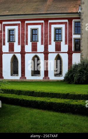 Von der mittelalterlichen Gotik bis zum Barock des 18. Jahrhunderts: Wechselnde Architekturstile, dargestellt durch diese bunte Palette des ehemaligen Zisterzienserklosters Zlatá Koruna oder der Goldenen Krone in Südböhmen, Tschechien. Spitz zulaufende Fenster im Erdgeschoss stehen im Kontrast zu viel später verbleiteten Lichtern darüber. Stockfoto