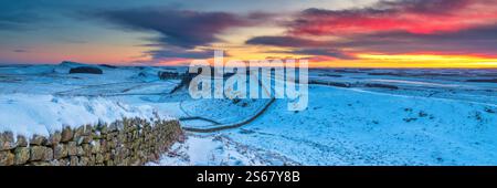 Blick auf die Hadrian's Wall im Winter bei Sonnenaufgang von Cuddy's Crags nach Osten in Richtung Housesteads Fort mit Schnee, Eis und Sonnenaufgang in Northumberland Stockfoto