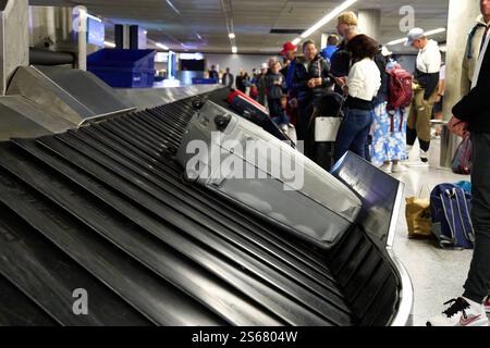 Deutschland - 12. Januar 2025: Gepäck auf dem Förderband am Flughafen, Passagiere, die in der Ankunftshalle auf ihren Koffer warten *** Gepäck auf dem Förderband am Flughafen, Fluggäste warten auf ihre Koffer in der Ankunftshalle Stockfoto