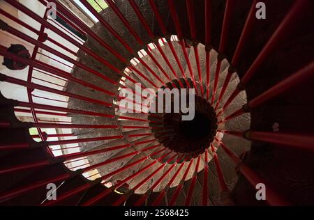 Blick von oben auf die steile Wendeltreppe mit roten Handläufen Stockfoto