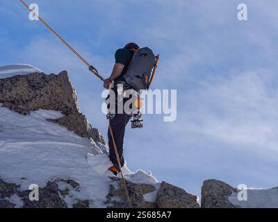 Adrenalinrausch auf der Aiguille du Midi – Climber steigt mit Full Gear einen steilen Felsen hinab, gesichert durch Rope im Herzen der französischen Alpen Stockfoto