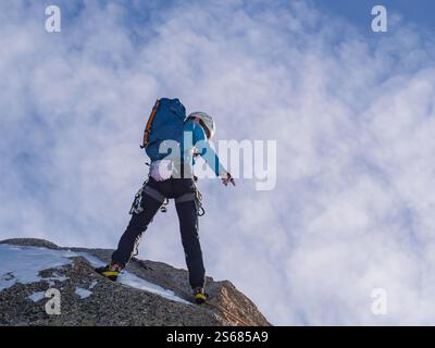 Adrenalinrausch auf der Aiguille du Midi – Climber steigt mit Full Gear einen steilen Felsen hinab, gesichert durch Rope im Herzen der französischen Alpen Stockfoto