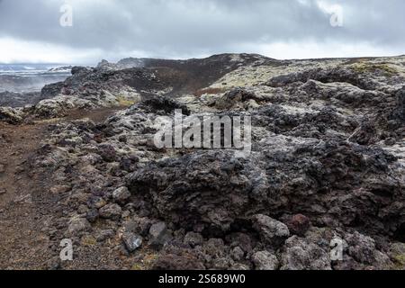 Vulkanische Felsformationen in den schwarzen Lavafeldern des Leirhnjukur-Vulkans in Island, gefrorenes Magma und dampfende Lüftungsöffnungen. Stockfoto