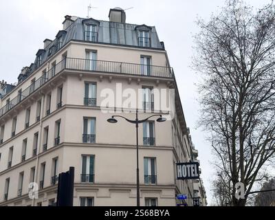 Klassisches Pariser Hotelgebäude unter bewölktem Himmel in der Nähe der belebten Straße Stockfoto