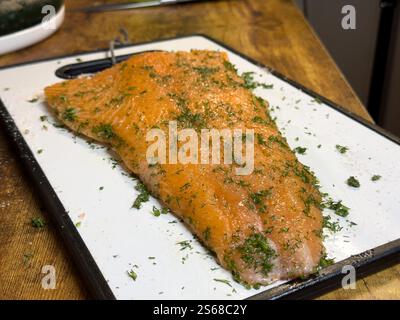 Frisch zubereitetes Lachsfilet garniert mit Kräutern auf einem Schneidebrett Stockfoto