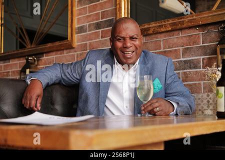 Ein elegant gekleideter schwarzer Geschäftsmann, der sich mit seinem Lieblingsgetränk in einer trendigen Bar entspannt. Stockfoto