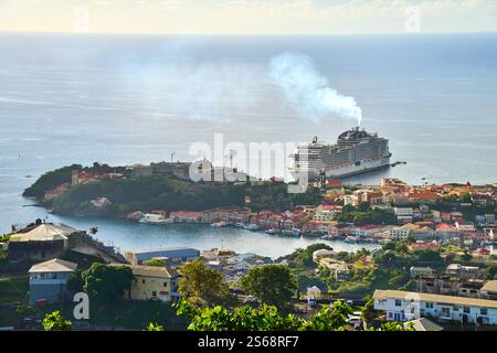 Saint George s, Grenada, Karibik - 10. Januar 2025: Blick auf das Kreuzfahrtschiff MSC Virtuosa im Hafen von Saint George s, der Hauptstadt von Grenada, mit der malerischen Karibikküste im Hintergrund *** Blick auf das Kreuzfahrtschiff MSC Virtuosa im Hafen von Saint George s, der Hauptstadt von Grenada, mit der malerischen Karibikküste im Hintergrund Stockfoto