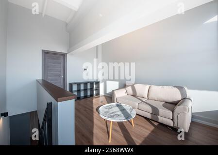 Heller, moderner Wohnbereich mit komfortablem Sofa, rundem Marmortisch, Naturholzboden und skandinavischem Design. Saubere Architektur Stockfoto