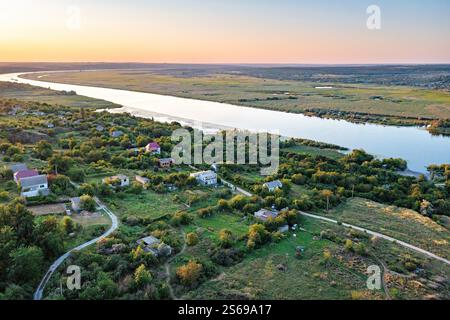 Die malerische Flusslandschaft bei Sonnenuntergang offenbart ruhige Dorfbeschaulichkeit und üppiges Grün. Luftaufnahme. Stockfoto