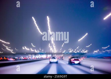 Fahren bei schlechtem Wetter mit Schnee auf der Stadtautobahn, Bewegungsunschärfe mit Lichtspuren, die durch Langzeitaufnahmen erzeugt werden Stockfoto