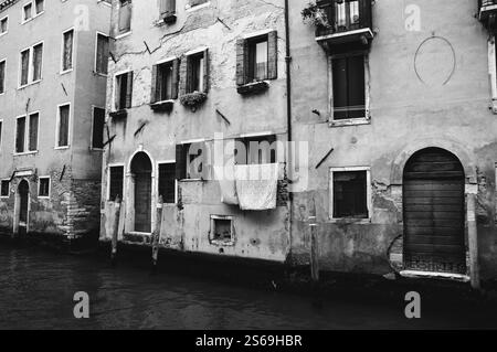 Leinen werden zum Trocknen über einem Kanal gehängt. Der Alltag in Venedig, Italien. Schwarzweißes historisches Foto. Stockfoto
