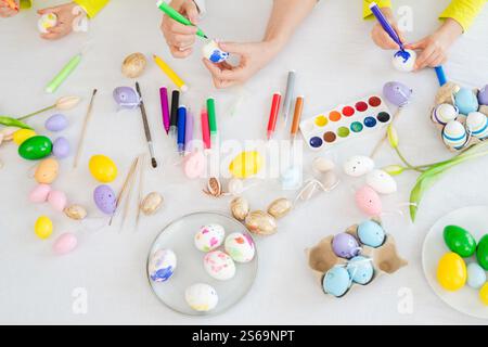 Frohe Ostern. Kleine Mädchen Großmutter Hände malen Eier und genießen die gemeinsame Zeit. Glückliche Familie bereitet sich auf Ostern vor. Tisch mit farbenfrohen Ei-Gemälden Stockfoto