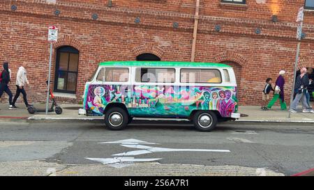 Ein lebendiger, handbemalter Volkswagen-Van mit psychedelischen Kunstwerken, mit kultigen Kulturfiguren, einer Skyline der Stadt und der Golden Gate Bridge Stockfoto