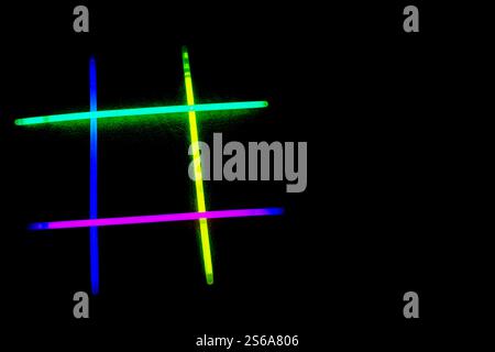 Neon-Leuchtstäbe sind im Hashtag-Symbol auf schwarzem Hintergrund angeordnet. IT-Konzept DER Internettechnologie Stockfoto