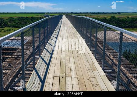Eine Brücke mit einem Holzsteg und einem Metallgeländer. Die Brücke ist lang und schmal, und das Geländer besteht aus Metall. Die Aussicht von der Brücke ist von einem Stockfoto