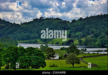 Lake District, Cumbria, England, Großbritannien – Bauernhöfe und Häuser liegen im Sommer auf den Hügeln rund um den Grasmere Lake unter blauem Himmel Stockfoto