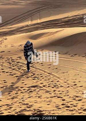 Ein älterer Mann, der mit Sandbrett unter dem Arm die Sanddüne hinaufläuft Stockfoto