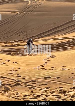 Ein älterer Mann, der mit Sandbrett unter dem Arm die Sanddüne hinaufläuft Stockfoto