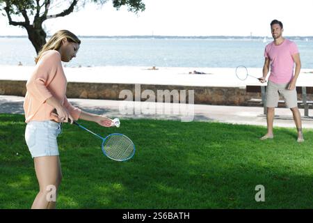 Ein Paar spielt Badminton auf Gras am Strand Stockfoto