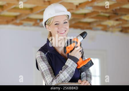 Attraktive junge Bauarbeiterin mit Bohrer Stockfoto