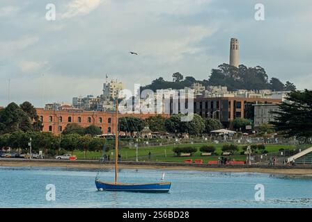 Maritimer Garten in der Aquatic Cove mit einem verankerten Segelboot und einem Coit Tower im Art déco-Stil auf dem Telegraph Hill in San Francisco Stockfoto