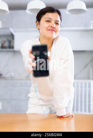 Lächelnde junge Frau, die ein Smartphone mit leerem Bildschirm zeigt Stockfoto