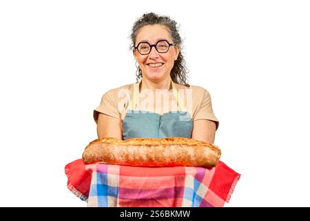Eine Frau mit Brille und Schürze hält einen langen Brotlaib Stockfoto