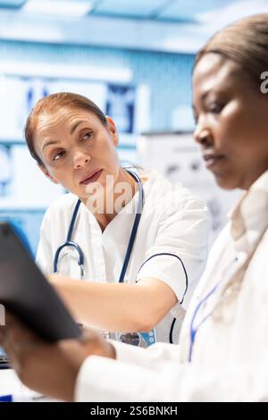 Mitarbeiter des Gesundheitswesens treffen sich in einer Klinik, um Röntgendaten zu analysieren, und treffen sich, um Röntgenaufnahmen und Krankenhausaufzeichnungen zu untersuchen. Lizenzierte Experten arbeiten an Behandlungsplänen und Teamwork zusammen. Stockfoto