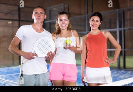 Drei lächelnde Spieler, Männer und zwei Frauen mit Paddelschlägern Stockfoto