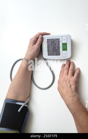 Hände einer älteren erwachsenen Frau mit einem tragbaren Blutdruckmessgerät, um ihre Gesundheit zu Hause zu überprüfen Stockfoto
