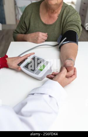 Der Arzt misst den Blutdruck einer älteren erwachsenen Frau mit einem digitalen Blutdruckmessgerät zu Hause Stockfoto