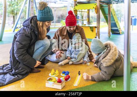 Glückliche Familie, die im Winter gute gemeinsame Zeit genießt und Brettspiele auf einem Spielplatz im Freien spielt Stockfoto