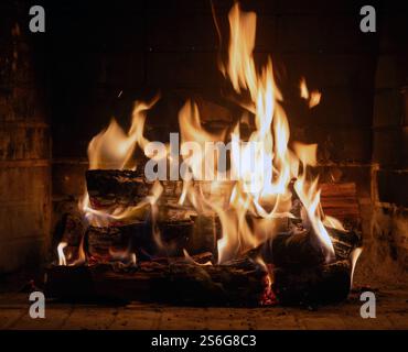Feuer im Kamin, Holzscheite und helle Flammen. Warmes Zuhause, Wärme. Weihnachtsfeiertage Stockfoto