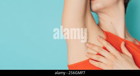 Eine behaarte weibliche Achselhöhle. Eine Frau, die natürliche Vegetation auf ihrem Körper zeigt. Panorama-Banner. Ein Ort für den Text. Stockfoto