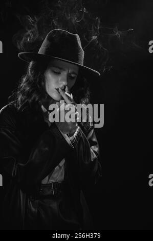 Dark Noir Porträt einer Detektivin, die eine Zigarette anzündet. Privatdetektiv, Spion, Ermittlungskonzept. Stockfoto