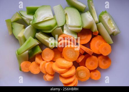 Frisch geschnittene Karotten und Chayote auf einem weißen Schneidebrett. Stockfoto