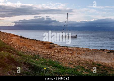 Das Segelboot Ankerte Nahe Der Rocky Shore Unter Dem Bewölkten Himmel Stockfoto