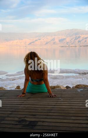 Entspannte junge Frau bewundert die ruhige Landschaft des Toten Meeres, Israel jordanische Berge im Hintergrund Stockfoto