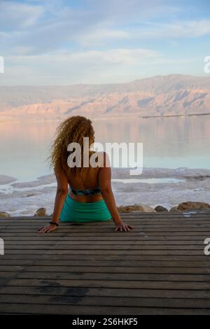 Entspannte junge Frau bewundert die ruhige Landschaft des Toten Meeres, Israel jordanische Berge im Hintergrund Stockfoto
